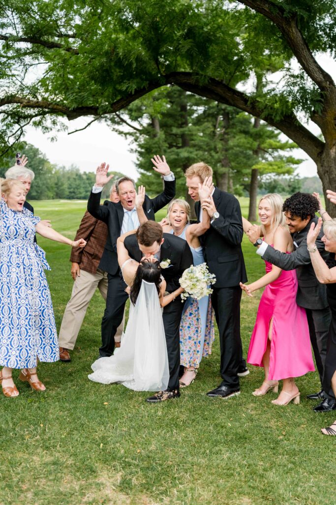 Bride and Groom kiss as the wedding party cheers them on