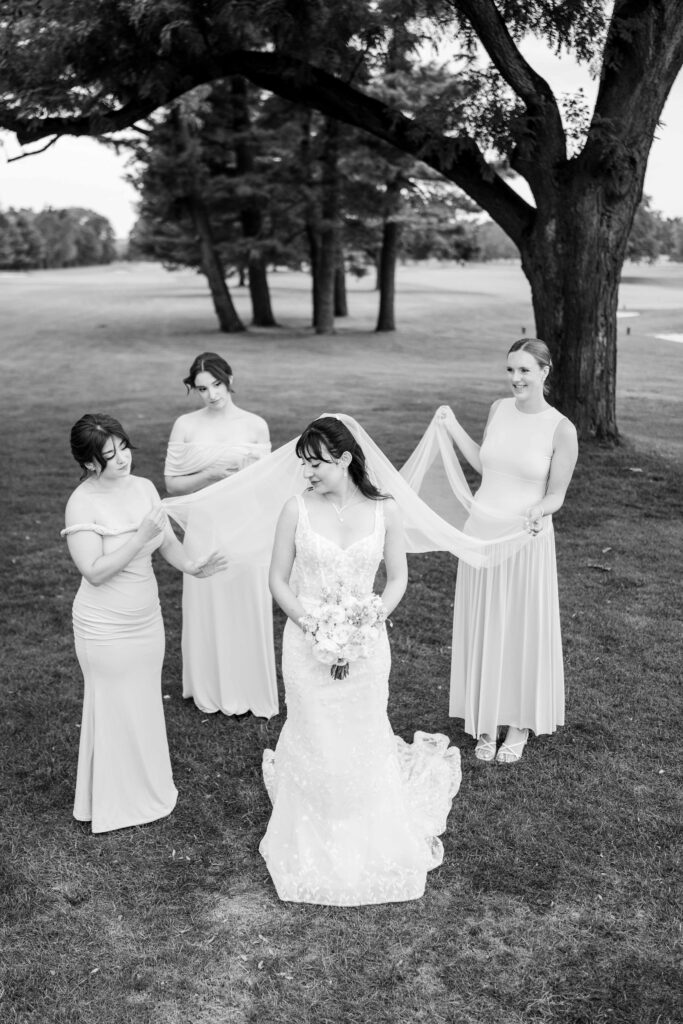 Bridesmaids lift up Sertaps veil for a bridal vogue portrait at Blythefield Country Club